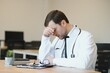 © Serhii - Stressed male doctor sat at his desk. Mid adult male doctor working long hours. Overworked doctor in his office. Not even doctors are exempt from burnout .