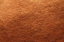 Detail texture of brown cane sugar grains, which are artfully arranged in a textured background. The fine, delicate grains are a rich, warm brown hue that creates a sense of comfort and familiarity. a