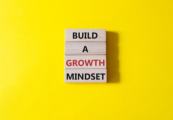 Build a growth mindset symbol. Concept words Build a growth mindset on wooden blocks. Beautiful yellow background. Business and Build a growth mindset world concept. Copy space.