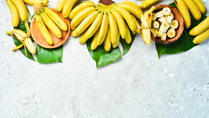 Wall Mural - A bunch of bananas and a sliced banana baby on a table, delicious, natural. On a stone background. Free copy space. Top view.