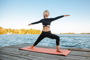 Woman doing yoga on mountain cliff at sunrise. Mountanious landscape