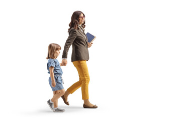 Full length profile shot of a woman walking carrying books and holding hands with a little girl