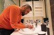 © Jelena - Handsome caucasian man washing himself in bathroom, morning routine