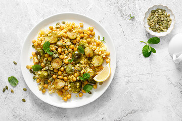 Sticker - Couscous brussels sprouts and chickpeas warm salad with pumpkin seeds. Healthy vegetarian diet food. Top view