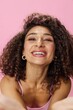 © SHOTPRIME STUDIO - Woman with curly afro hair dancing in pink top and jeans on a pink background, smiling, stretching her arms into the camera, copy space