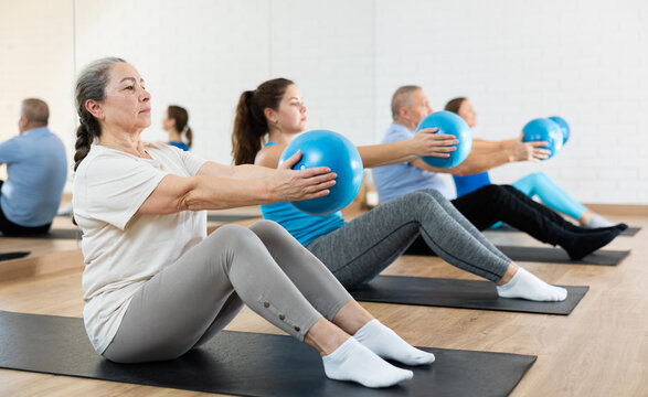 people of different ages clutching pilates ball in hands during group workout. active lifestyle and 
