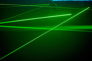 Bright green neon laser lights illuminate the darkness creating lines and triangle shapes in sci-fi effect.
