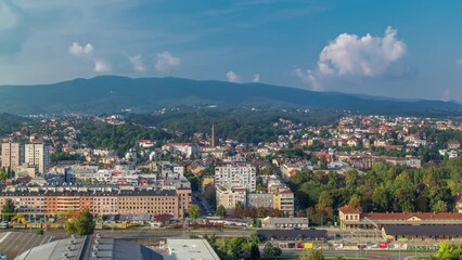 Wall Mural - Aerial panorama of the city center timelapse of Zagreb, Croatia, with modern and historic buildings, mountains on background. Top view from skyscraper with cloudy blue sky