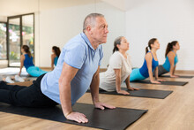 Group Of Young Mature Old People In Sportswear Exercising Pilates While Stretching On Mats In Rehabilitation Center