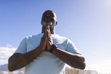 African American Senior Man With Joined Hands Meditating On The Terrace At Home
