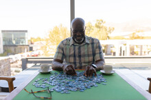 African American Senior Man Solving Jigsaw Puzzle At Home