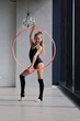 Cute teenage girl doing gymnastics at home. The girl spins the hoop.