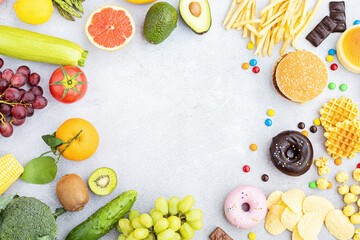 Flat lay of Healthy and unhealthy food from fruits and vegetables vs fast food, sweets and pastry on gray concrete background. Diet and detox against calorie and overweight lifestyle concept.