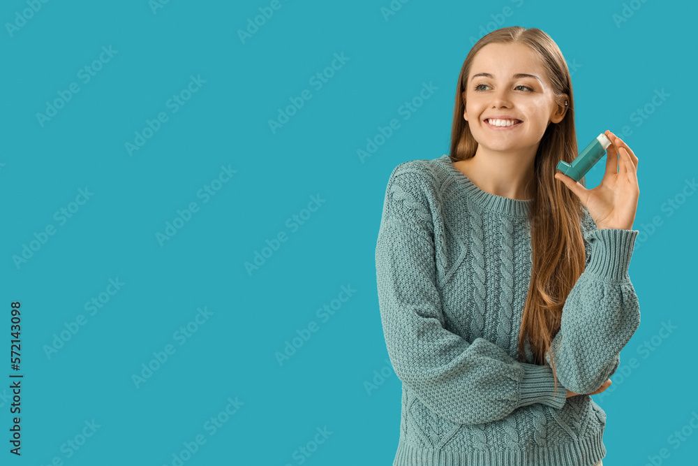 Young woman with inhaler on blue background