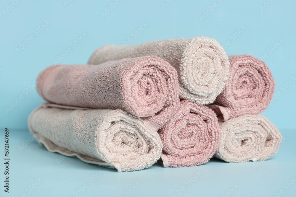 Heap of rolled towels on color background