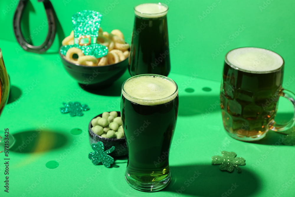 Glasses of beer, snacks and decor on green background. St. Patrick's Day celebration