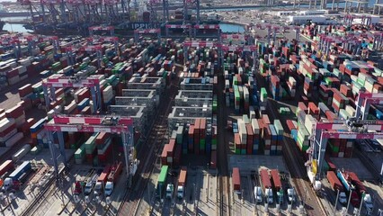 Wall Mural - Daytime aerial view of an intermodal container shipping stock yard unloading vessels at port.