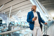 Black man waiting in airport with phone, smile and luggage in terminal for business trip. Technology, travel and happy businessman with international destination checking flight schedule app online.
