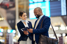 Businessman, Airport And Passenger Assistant Helping Traveler In Departure, Flight Time Or Passport Information. Black Male With Female Airline Service Agent For Advice On Travel, Directions Or FAQ