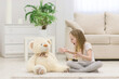 © Andrii - Photo of little blond girl talking to her white teddy bear.