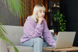 © ViDi Studio - Bored sad young IT woman wear casual clothes hold use work on laptop pc computer sits on grey sofa couch stay at home hotel flat rest relax spend free time in living room indoor People lounge concept