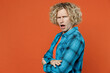 © ViDi Studio - Side view indignant sad young blond caucasian man wearing blue shirt orange t-shirt look camera holding hands crossed folded isolated on plain red background studio portrait. People lifestyle concept.