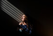 © Cavan Images - Profile of woman with eyes closed in a patch of light a dark room.