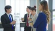 © M Stocker - A group of young Asian business people having fun talking and wearing suit hold a cup of coffee in the modern office