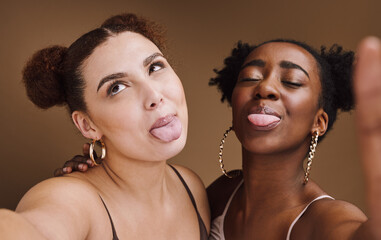 Canvas Print - Beauty, friends and tongue with selfie of black women for social media, skincare and fashion. Happy, silly and picture with funny face of girl for internet, comic and crazy in brown background studio