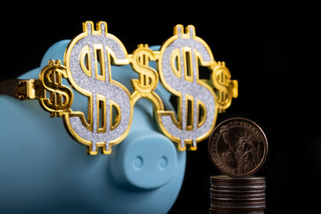 Blue piggy bank in glasses with the symbol of the dollar and a coin in denominations of 1 american doollar