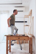 © astrosystem - Man assembling new wooden shelf and furniture in the apartment.