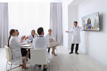 Lecture with online participant. Doctors in meeting room. Using tv for videoconference