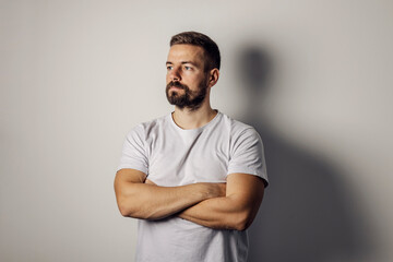 Portrait of a bearded man standing with arms crossed.