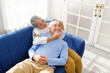 © artitwpd - Portrait of happy Asian senior couple living together, hug, touching and embracing with a smile on the sofa in the living room. Retirement living together at home.