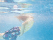 © Austockphoto - Underwater image of girl coming up to breath air in backyard pool while palying