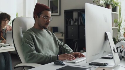 Young developer working with computer program on computer sitting at his workplace