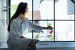 © Wosunan - Woman sitting on bathtub wearing white bathrobe in modern bathroom at home with rose leaves to enhance the fragrance of the bath atmosphere