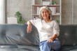 Happy mature woman asian people sitting on sofa in relax time at home living room.