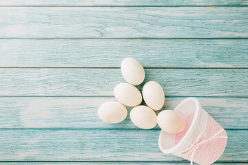 Wall Mural - Happy Easter Day Concept. Top view of holiday banner background design white easter eggs and basket on blue wooden background with empty copy space, celebration greeting card