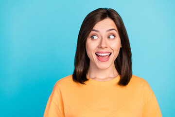 Sticker - Portrait of adorable impressed astonished girl with long hairdo dressed yellow t-shirt look empty space isolated on blue color background