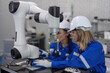 © Tongpool - Female senior robotic engineer in modern factory teach new comer operate and maintenance robot arm
