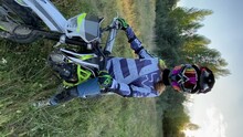 Close-up of a beautiful young girl in a motorcycle helmet, a biker on an enduro motorcycle in ski goggles. Portrait of a girl motorcyclist enduro, pit bike. Equipment, expedition.Vertical orientation 
