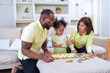 © Tongpool - Young family with small daughter sitting on sofa playing arrange alphabet in the living room