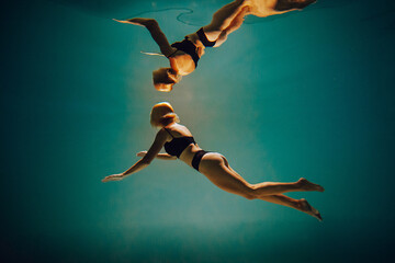 Art work. A slender, tanned girl with an athletic figure and blond hair, in black lingerie, dives underwater in the pool. Aesthetic image for your design or decoration.