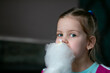 © Татьяна Волкова - Portrait of amazing little girl with fair hair holding eating delicious white cotton candy candyfloss looking at camera.
