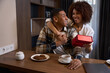 © Svitlana - Cute multiracial wife giving gift box to husband at hotel breakfast