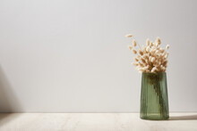 Green Glass Vase With Dry Flowers Stand On A Wooden Desk, Background White Wall