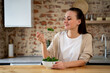 © Grustock - Healthy woman eats a delicious and healthy salad from a bowl at her dining table.