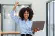 © amnaj - Businesswoman raising her hand in congratulation with document and laptop computer