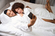 © Svitlana - Charming newlyweds in bathrobes take a selfie on the bed